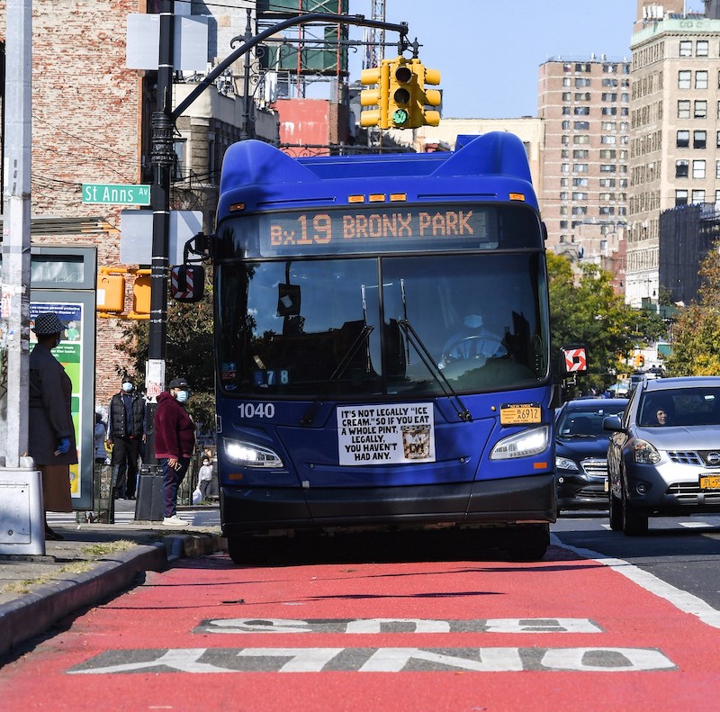 A bus driving in a bus lane. The bus lane is painted red. 