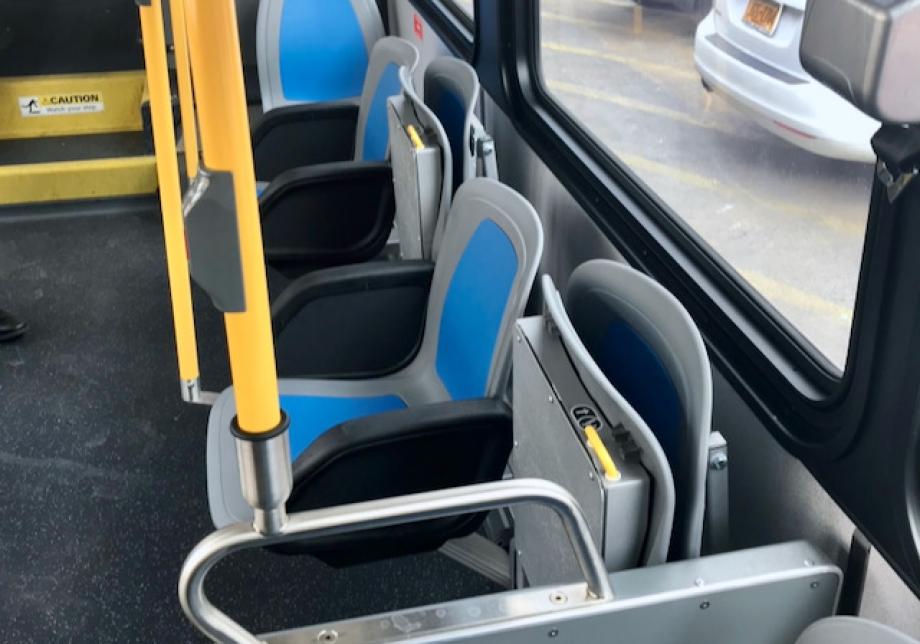 side-facing seats line the streetside of the bus. Four seats alternate between flipped-up seats and stationary seats.